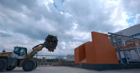 In a woodworking plant, a tractor loader uses a grab to transport a logs Stock Footage 161977904