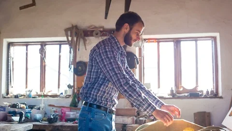 In a woodworking workshop, a young carpenter wears a protective apron Stock Footage 85519116