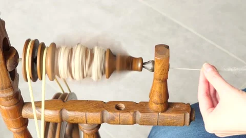 Wool being spun onto the bobbin of an old, castle-style spinning wheel. Stock Footage 232394998