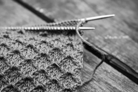 Wool yarn pattern with knitting needles on wooden background, monochrome Stock Photos