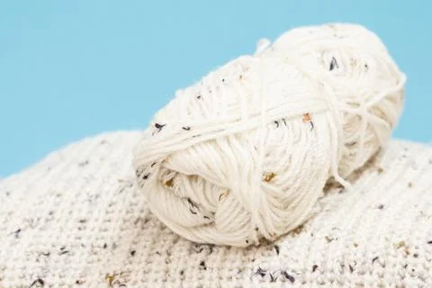 Woolen pullover and yarn for knitting. Skeins of natural wool yarn on blue Foto stock