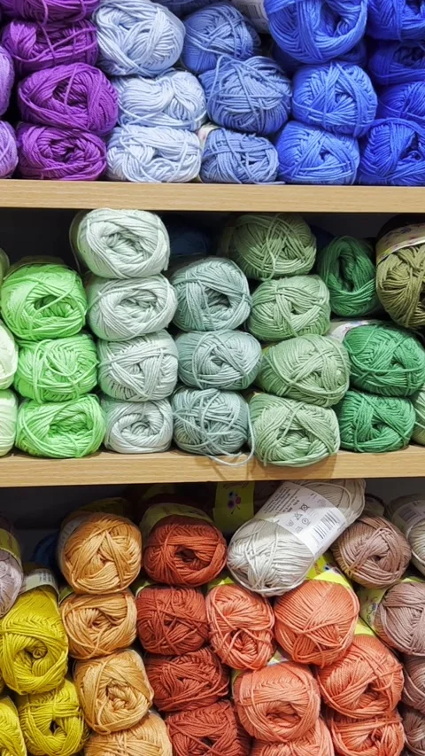 Woolen threads of different colors in the store on the shelf. Vertical video Video stock 250387432