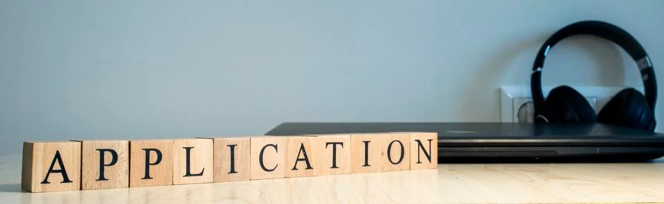 The word application is written. Computer and headset in the background. Stock Photos