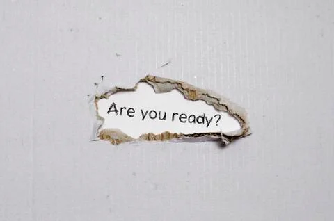 The word are you ready appearing behind torn paper. Stock Photos