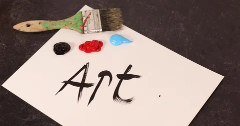 The word art hand picking up paintbrush and smearing wet paint over word Stock Footage 126126568