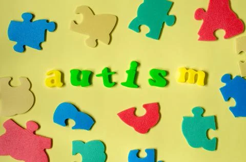 The word autism from colored letters with elements of a multicolored puzzle. Stock Photos