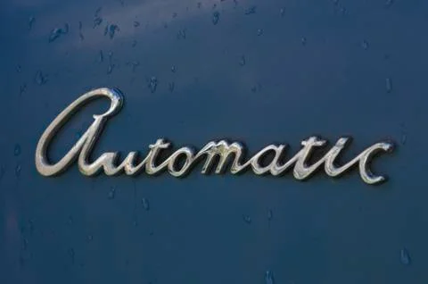The word automatic in chrome on a blue painted background Stock Photos