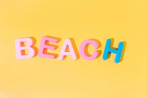 Word beach in colors on yellow background. copy space. summer concept Stock Photos