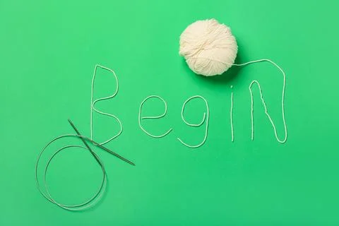 Word BEGIN made of knitting yarn with needles on green background Stock Photos