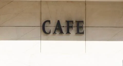 The word cafe is written on the marble wall. Light brown black font on the wa Foto stock