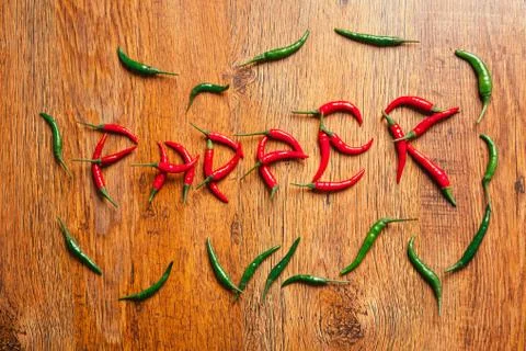 Word from chili peppers on a wooden background Stock Photos