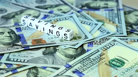 Word from cubes "savings" on the spinning surface of American dollars Stock Footage 70580795