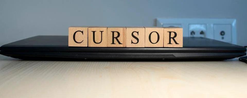 The word cursor is written. Computer and headset in the background. Stock Photos