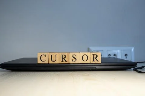 The word cursor is written. Computer and headset in the background. Stock Photos