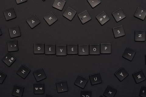 The word "develop" assembled from black keyboard keys on a dark background Stock-Fotos