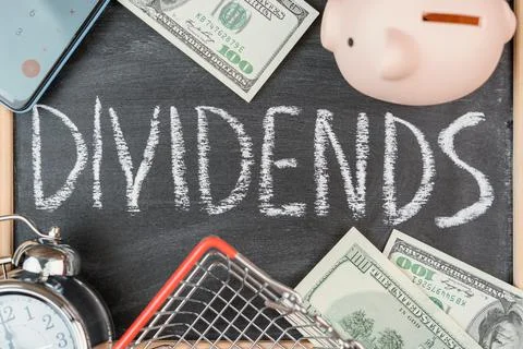 The word DIVIDENDS on a black chalk board in a frame, top view . The concept  Stock Photos