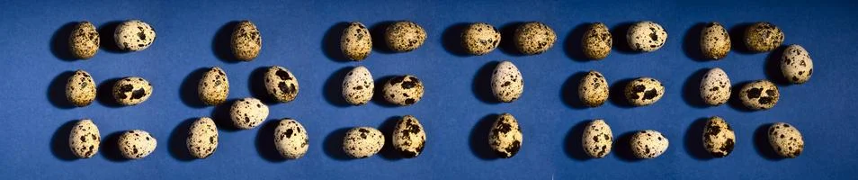 Word EASTER. Creative quail egg layout on blue background. Quail eggs pattern 스톡 사진
