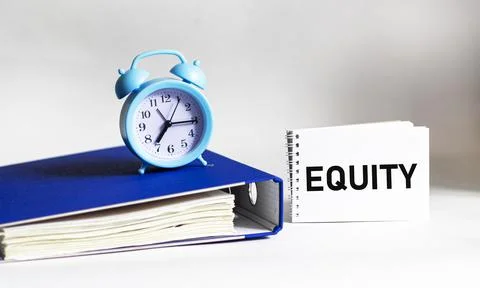 The word EQUITY is written on a notepad. Document folder and alarm clock on w Stock Photos