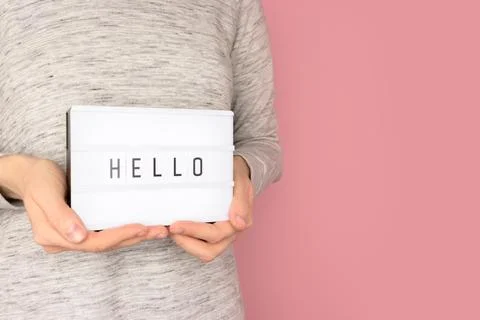 Word Hello. Female hands hold lightbox with letters. Stock Photos
