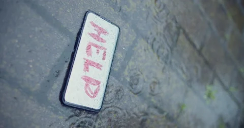 Word HELP on the screen of smartphone, wet ground, crime scene hijack concept Stock Footage 133002830