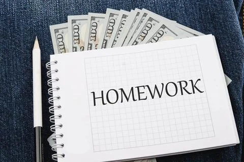 Word HOMEWORK on a checkered notebook against the background of American pape Stock Photos
