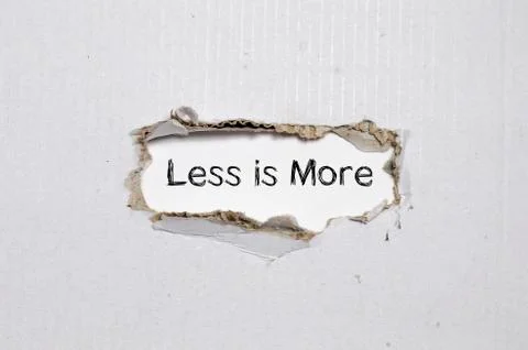 The word less is more appearing behind torn paper. Stock Photos