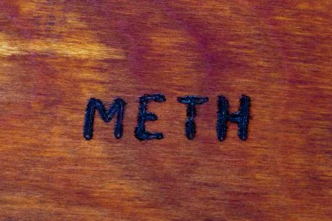 The word meth for Methamphetamine - burned by hand with woodburner on brown w Фото
