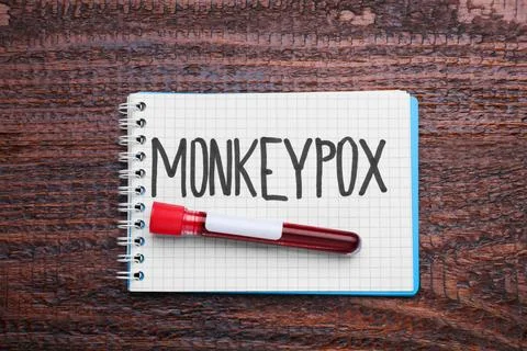 Word Monkeypox written in notebook and test tube with blood sample on woode.. Stock Photos