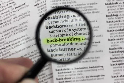 The word or phrase back-breaking in a dictionary. Stock Photos