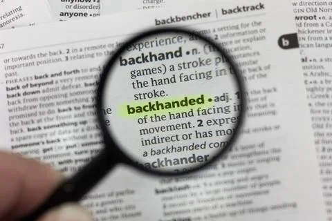 The word or phrase backhanded in a dictionary. Stock Photos