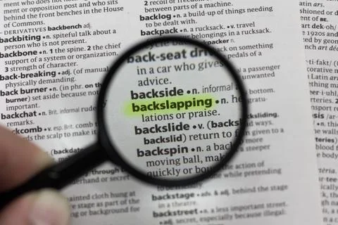 The word or phrase backslapping in a dictionary. Stock Photos