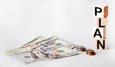 The word PLAN composed of building blocks, nearby dollars and coins isolate.. Stock Photos