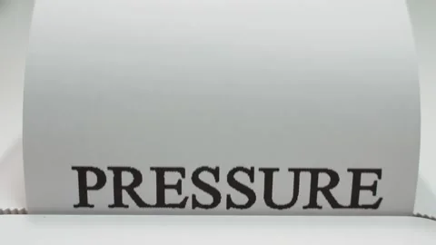 The word PRESSURE is printed in large black letters on white paper, close-up Stock Footage 324699759
