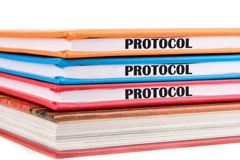 A word PROTOCOL written on the ends of notebooks lying on top of each other o Stock Photos