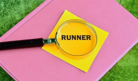 The word RUNNER focused through a magnifying glass on a yellow sticker on a n Stock Photos