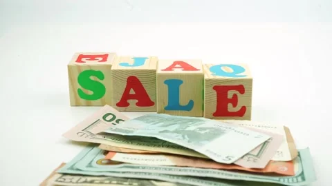 The word sale made of cubes. A bundle of dollar and euro banknotes Stock Footage 149136313