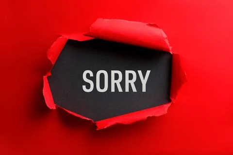 Word Sorry on black background, view through torn red paper Stock Photos