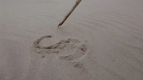 The word SOS. Hand drawing intricate patterns in fine sand with a stick, Stock Footage 317041708