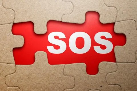The word SOS is revealed through a missing section of a cardboard jigsaw pu.. Stock Photos