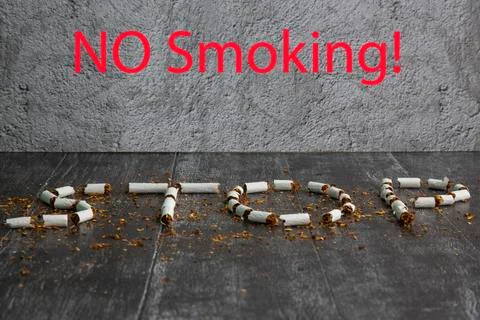 The word stop is written using cigarettes on a dark background. Concept: stop Stock Photos