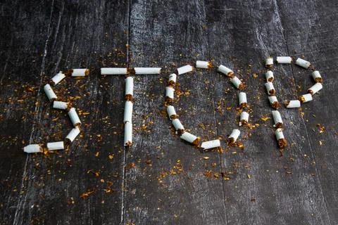 The word stop is written using cigarettes on a dark background. Concept: stop Stock Photos