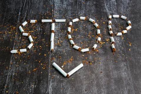 The word stop is written using cigarettes on a dark background. Concept: stop Stock Photos