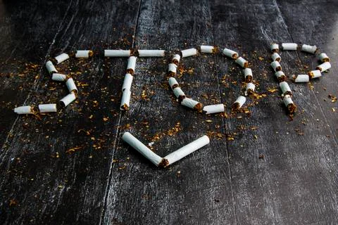 The word stop is written using cigarettes on a dark background. Concept: stop Stock Photos