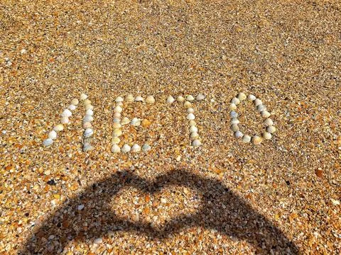 Word summer is lined with scallops shells on the coastal sand. A shadow from  Stock Photos