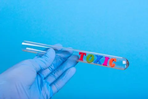 Word toxic in test-tube holding a gloved hand Stock Photos