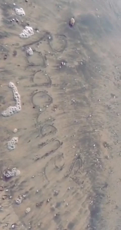 Word written in sand on beach with ocean waves Stock Footage 328564658