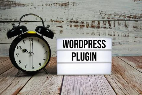 Wordpress Plugin text on light box with alarm clock on wooden background Stock Photos