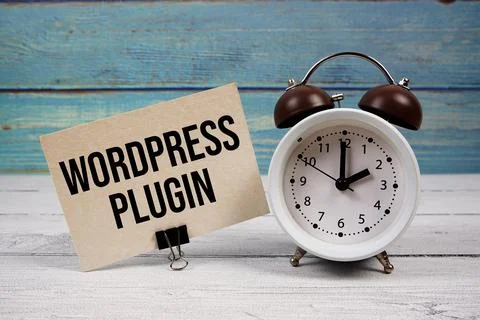 Wordpress Plugin text written on paper card with alarm clock on wooden back.. Stock Photos