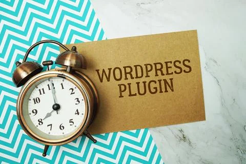 Wordpress Plugin text written on paper card with alarm clock on marble back.. Stock Photos