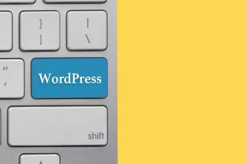 WORDPRESS text on keyboard over yellow background. Business and technology co Stock Photos